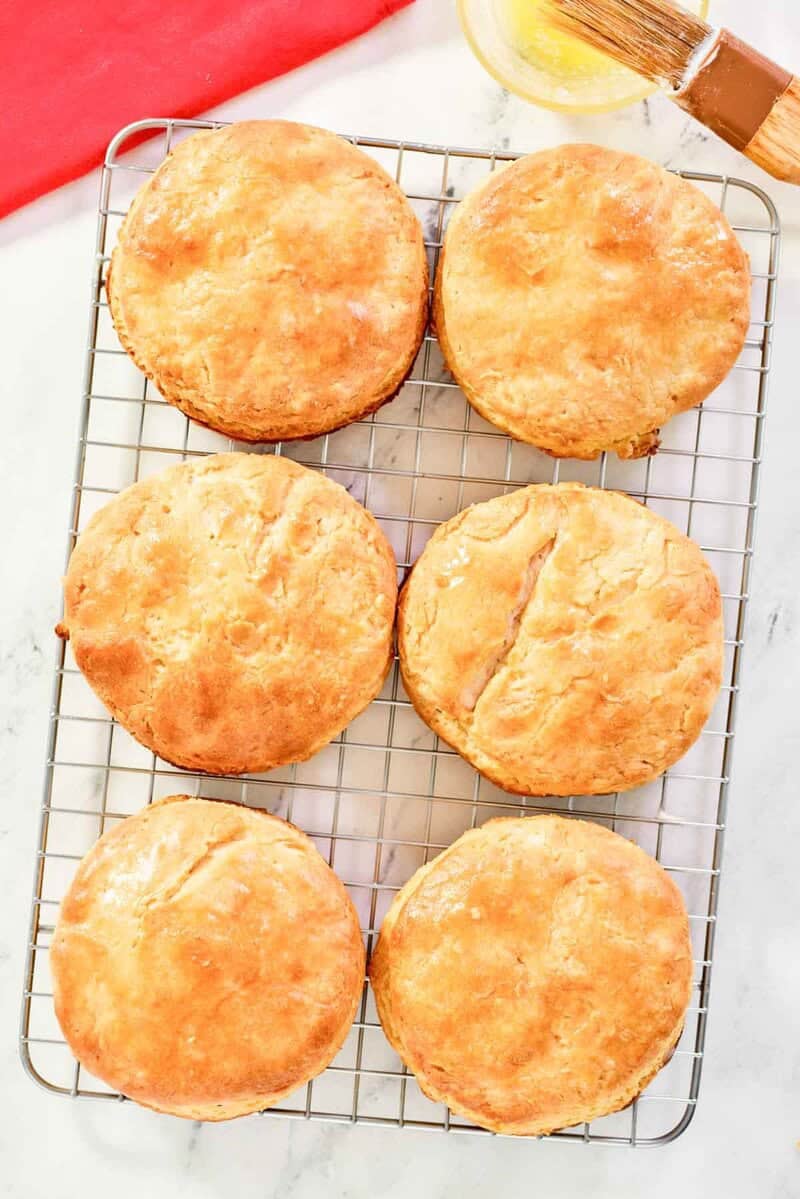 Copycat Bojangles biscuits on a wire rack and a small cup of melted butter.