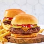 Homemade chili's big qp burger with cheese and fries on a wood board.