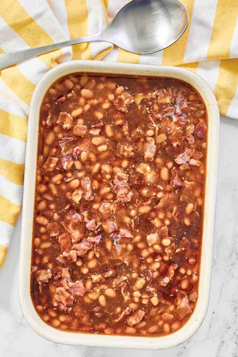 Copycat Durgin Park Boston baked beans, serving spoon, and kitchen towel.
