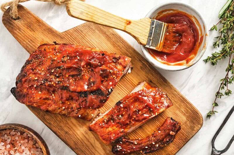 Homemade St. Louis style bbq sauce in a small cup and on a rack of pork ribs.