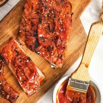 Homemade St. Louis style barbecue sauce in a small cup and on a rack of ribs.