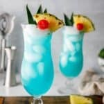 Two copycat Olive Garden Blue Hawaiian cocktails in hurricane glasses.