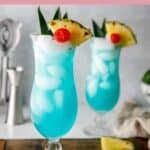 Two homemade Olive Garden Blue Hawaiian drinks in hurricane glasses.