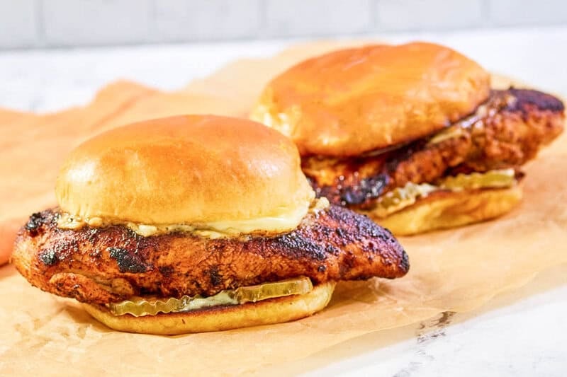 Copycat Popeyes blackened chicken sandwiches on parchment paper.