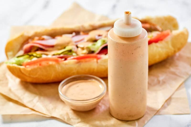 Copycat subway baja chipotle sauce in a squeeze bottle, bowl, and on a sandwich.