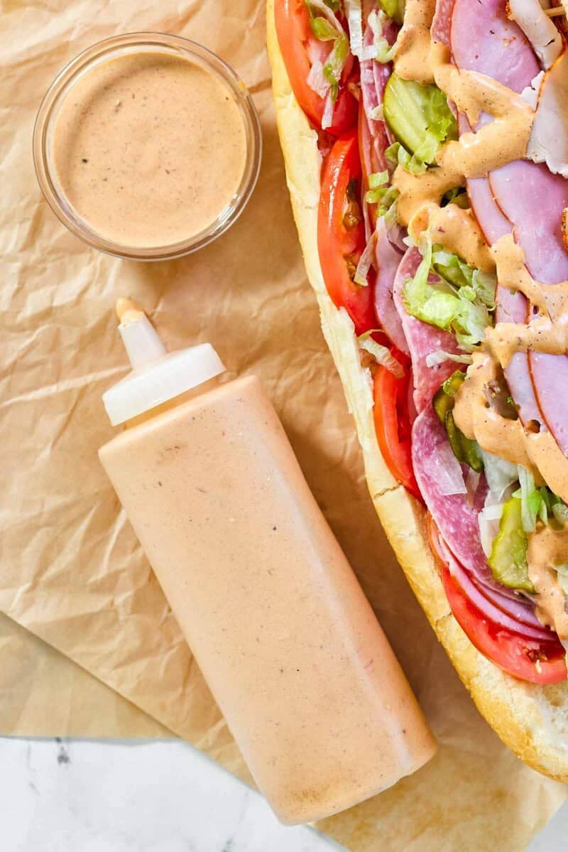 Copycat subway baja chipotle sauce in a bowl, squeeze bottle, and on a sandwich.