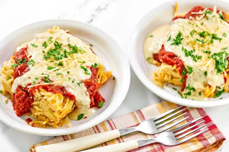 Copycat Cheddar's spasagna in two shallow bowls and two forks in front of them.