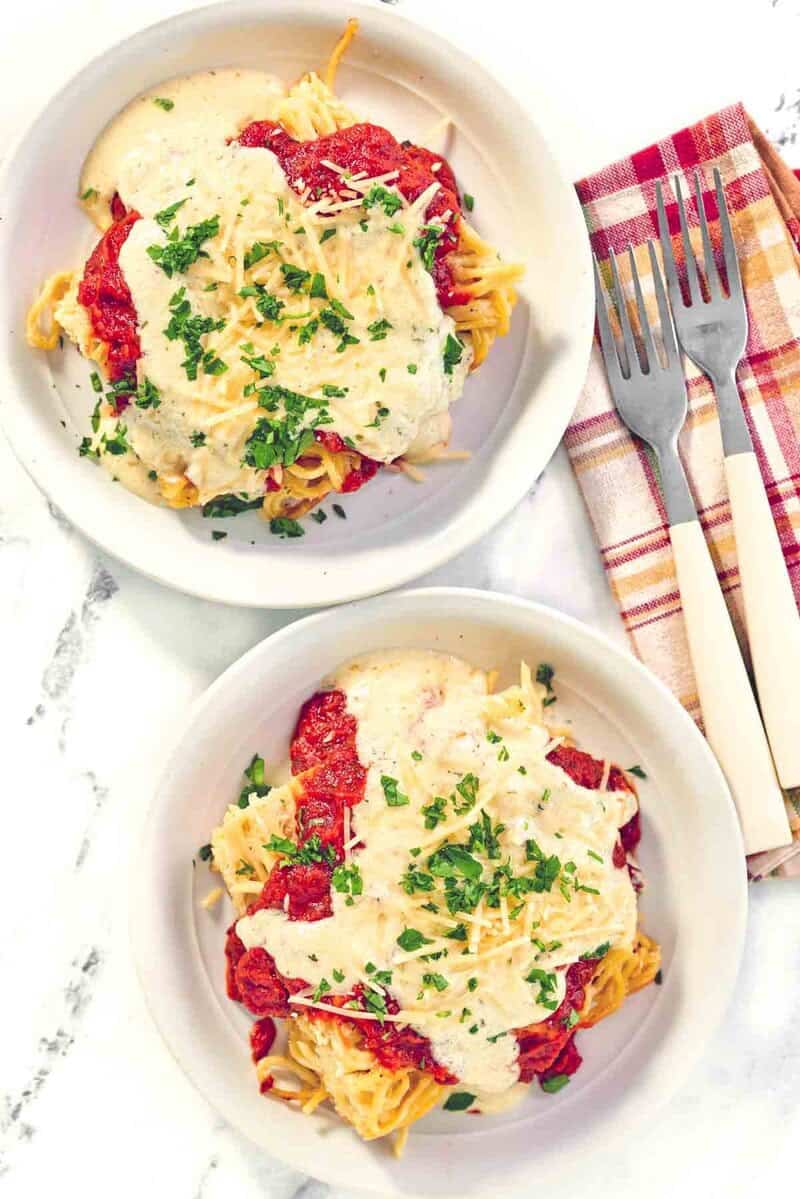 Copycat Cheddars spasagna in two shallow bowls and two forks beside them.