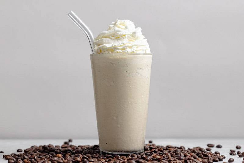 Copycat Chick-fil-A frosted coffee with whipped cream in a glass and coffee beans around it.