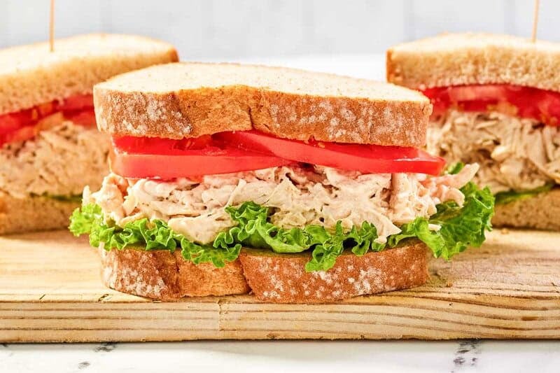 Copycat chicken salad chick barbie-q chicken salad sandwich with lettuce and tomato.
