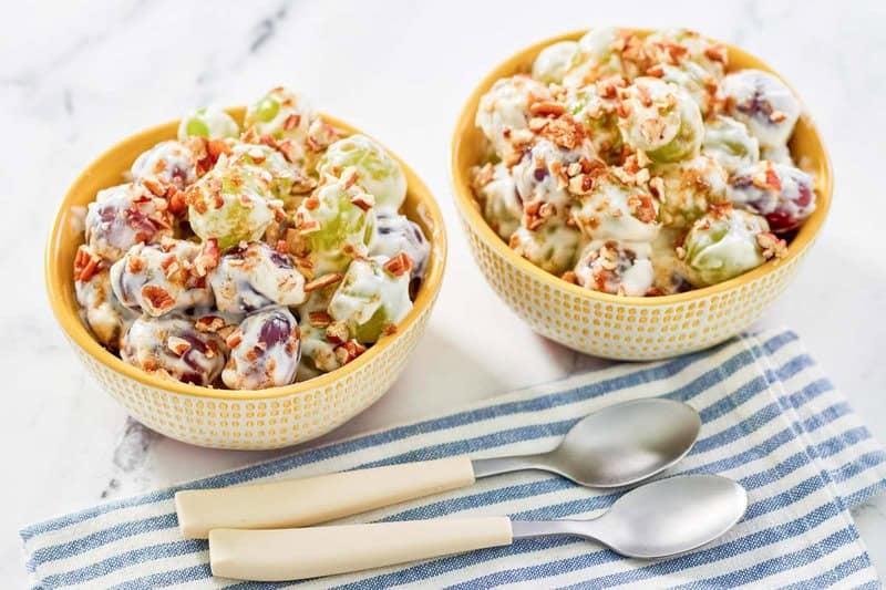 Copycat chicken salad chick grape salad in two bowls and two spoons in front of them.