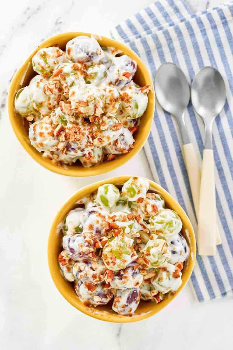 Copycat chicken salad chick grape salad in two bowls and two spoons next to them.