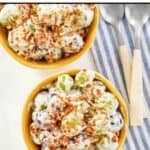 Two bowls of homemade chicken salad chick grape salad and two spoons.