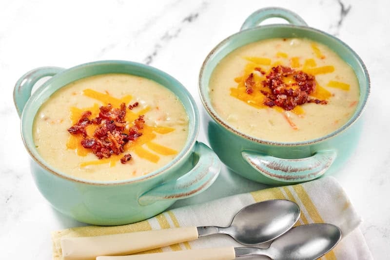 Copycat Jason's Deli Irish potato soup in two bowls and two spoons by them.