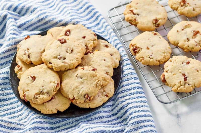 Copycat Keebler pecan sandies cookies piled on a plate and on a wire rack.