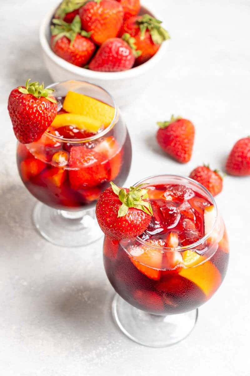 Two glasses of copycat Olive Garden sangria and a bowl of strawberries.