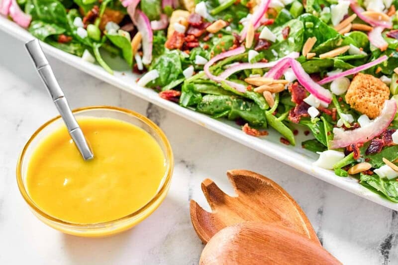 Copycat Simon and Seafort's mustard dressing in a bowl next to a salad.