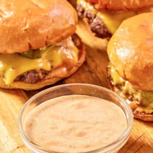 Copycat Sonic smasher sauce in a small bowl and burgers behind it.