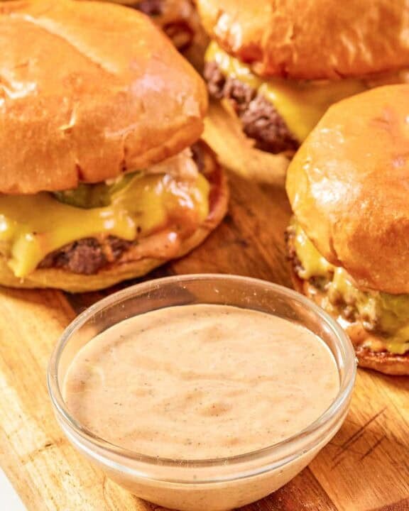 Copycat Sonic smasher sauce in a small bowl and burgers behind it.