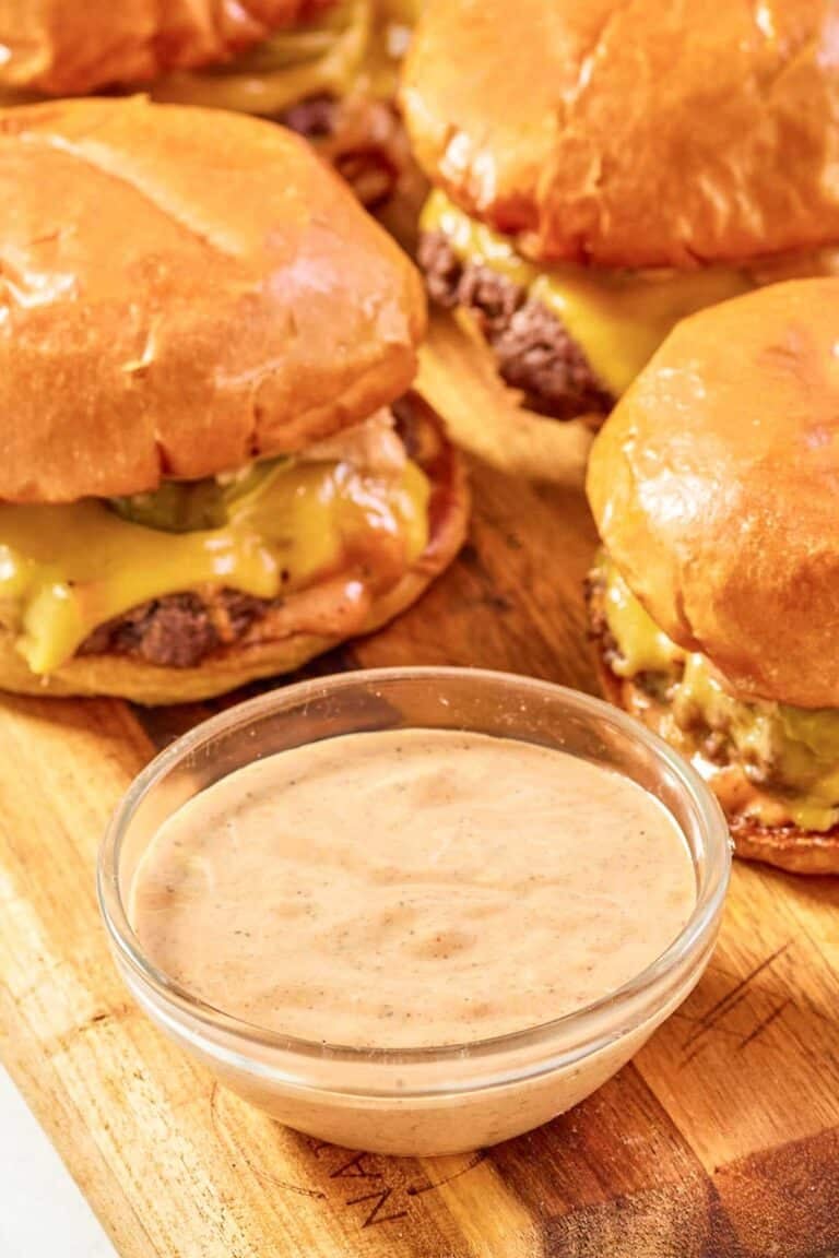 Copycat Sonic smasher sauce in a small bowl and burgers behind it.