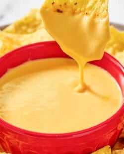 Copycat Taco Bell nacho cheese and a tortilla chip dipped in the sauce.