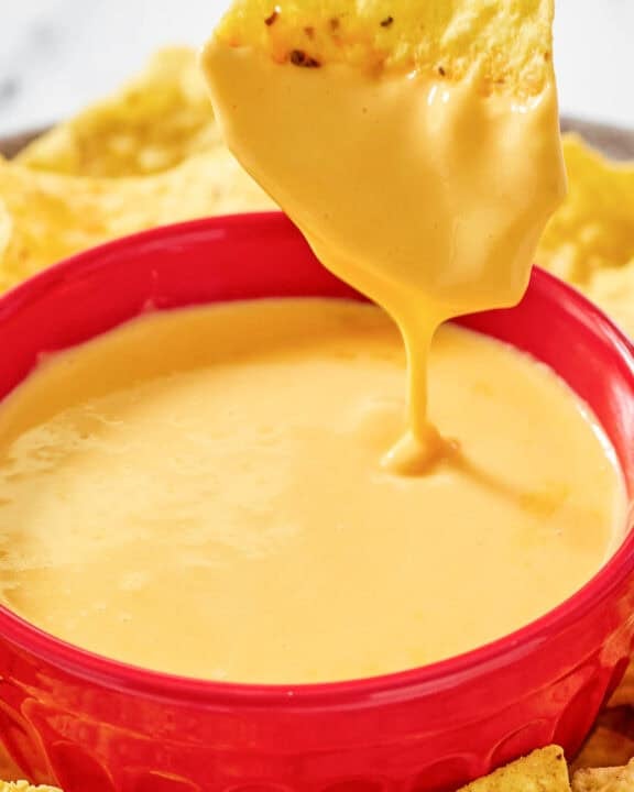 Copycat Taco Bell nacho cheese and a tortilla chip dipped in the sauce.