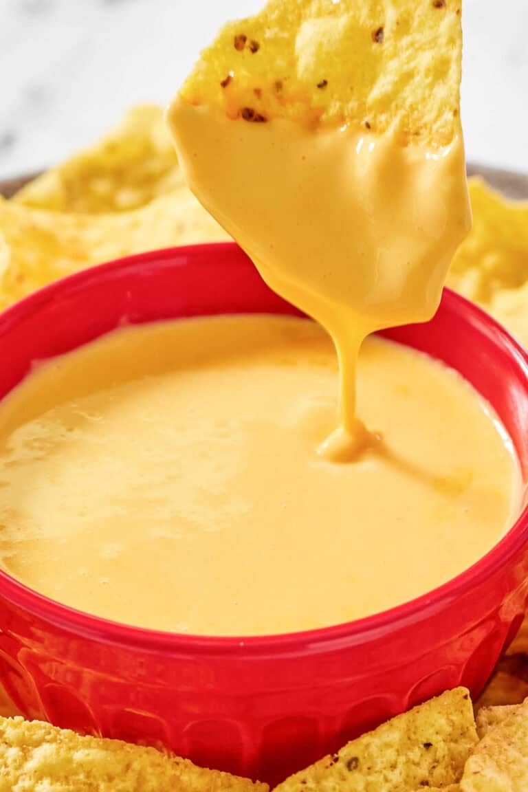 Copycat Taco Bell nacho cheese and a tortilla chip dipped in the sauce.