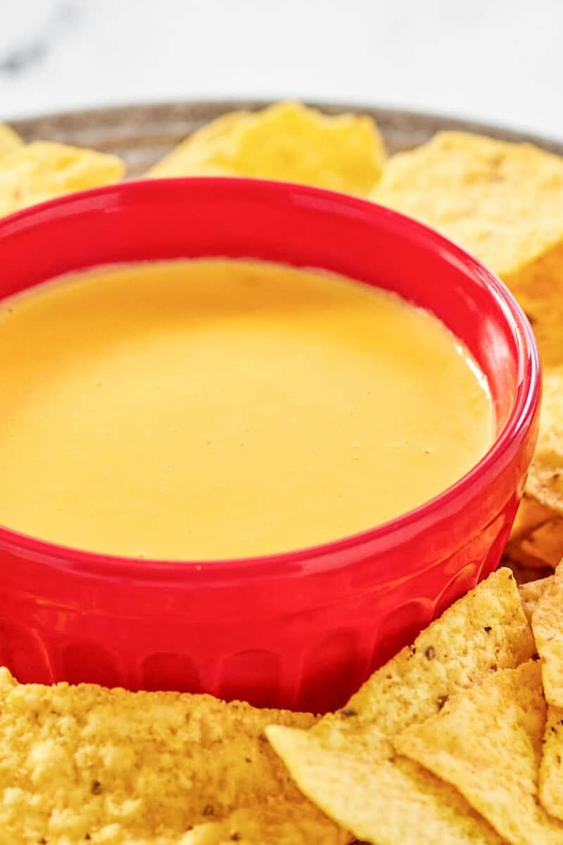 Copycat Taco Bell nacho cheese sauce in a bowl and tortilla chips by it.