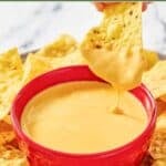 Homemade Taco Bell nacho cheese sauce and a tortilla chip dipped in it.