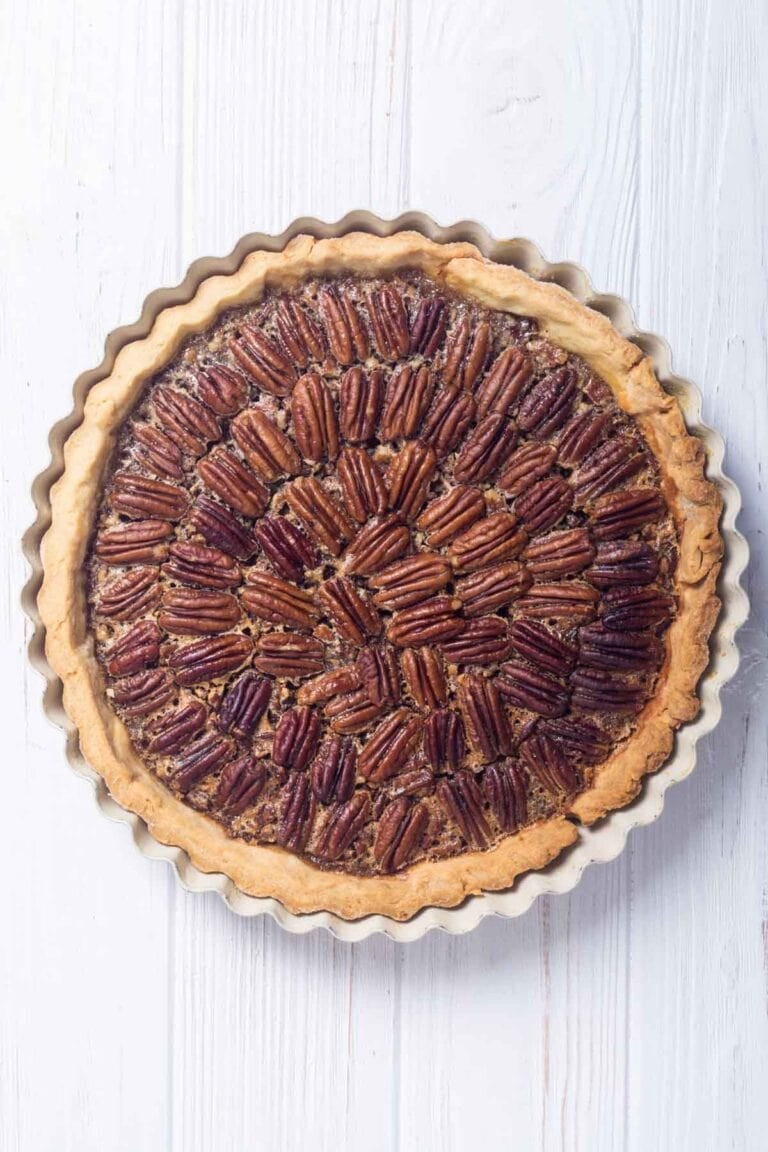 A whole copycat Taste of Texas pecan pie on a wood surface.