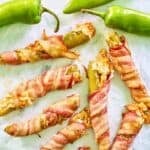 Bacon-wrapped cheese-stuffed hatch green chile peppers on parchment paper.