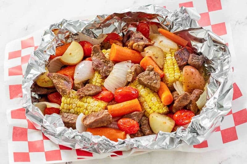Copycat Cracker Barrel campfire beef meal in foil on a parchment paper lined platter.
