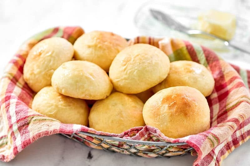 Copycat golden corral yeast dinner rolls in a serving basket and butter in a butter dish.