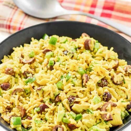Rice-A-Roni artichoke salad with curry in a large bowl and a large spoon behind it.