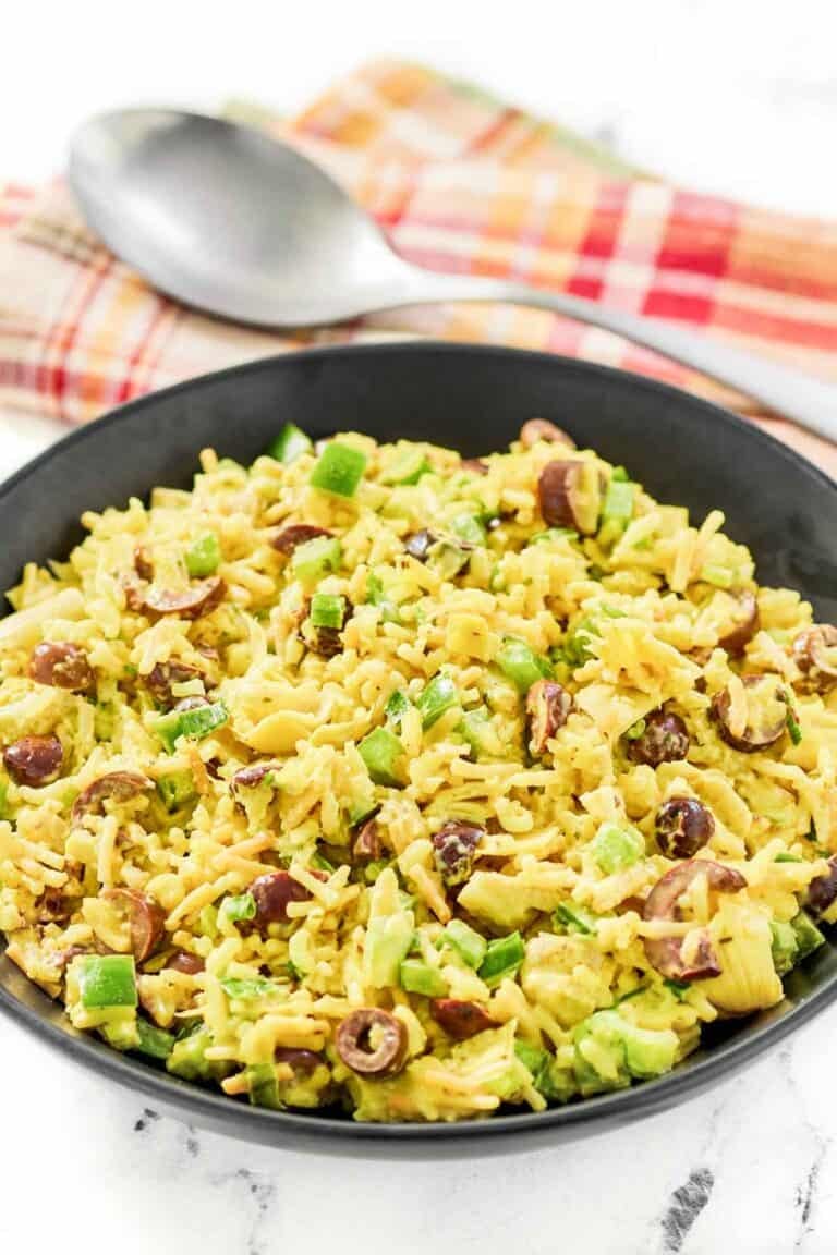 Rice-A-Roni artichoke salad with curry in a large bowl and a large spoon behind it.