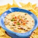 Homemade HEB brisket queso dip topped with pico de gallo and served with tortilla chips.