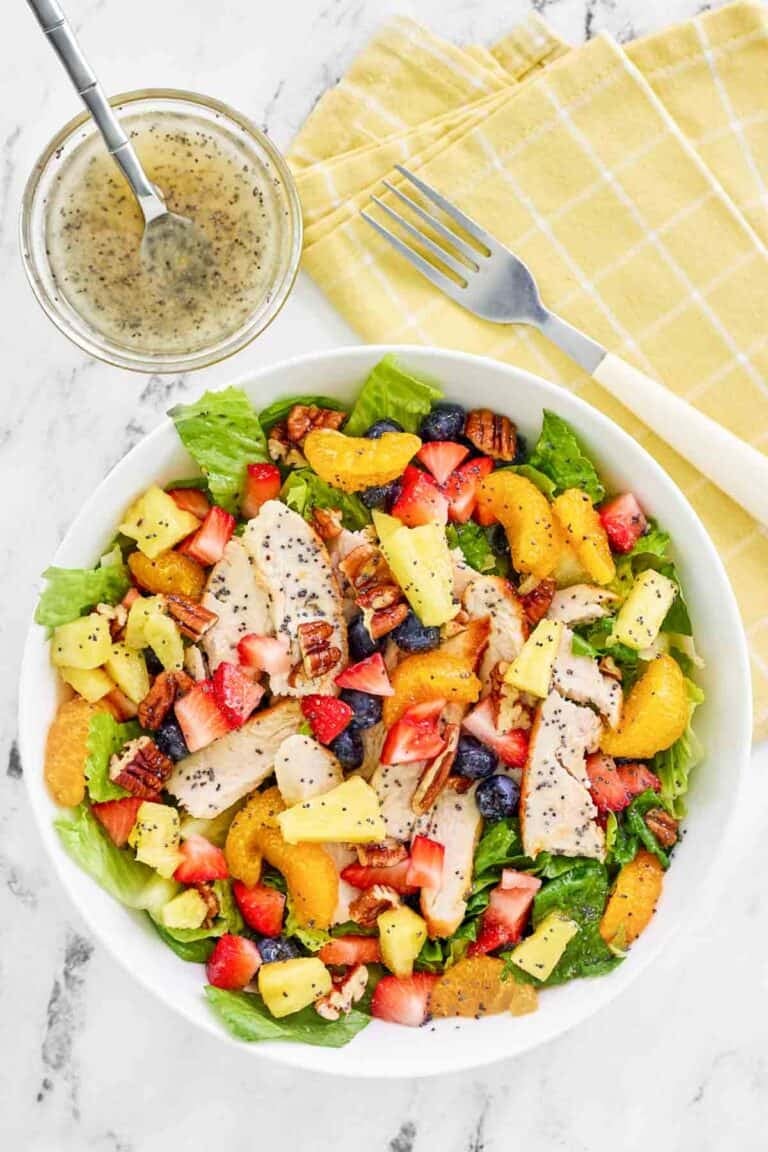 Copycat Panera strawberry poppyseed chicken salad, the dressing in a bowl, and a fork.