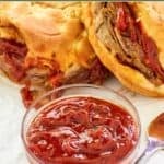 Homemade Arby's red ranch sauce in front of two roast beef sandwiches.
