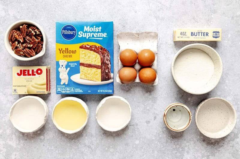 Ingredients for rum cake arranged on a flat surface: cake mix, pudding mix, eggs, butter, sugar, pecans, and liquids.