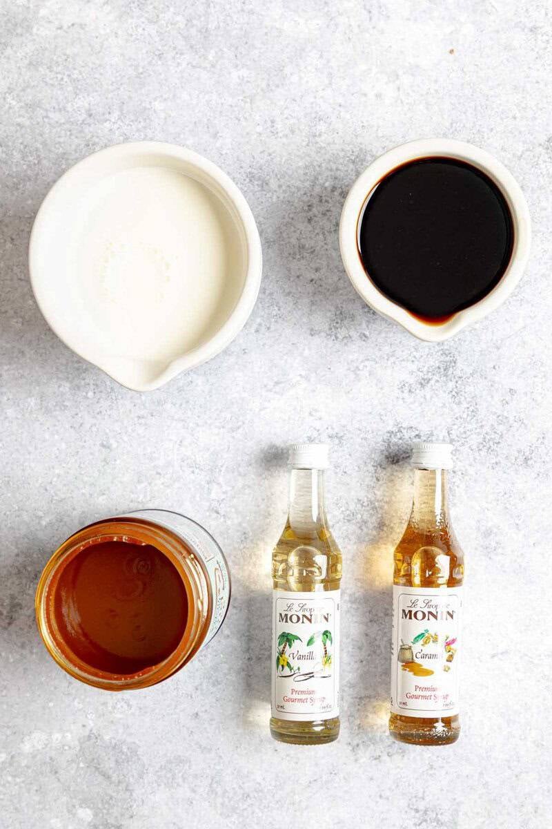 Ingredients for a Dutch Bros Golden Eagle: espresso, half-and-half, caramel sauce, and bottles of vanilla and caramel syrup.