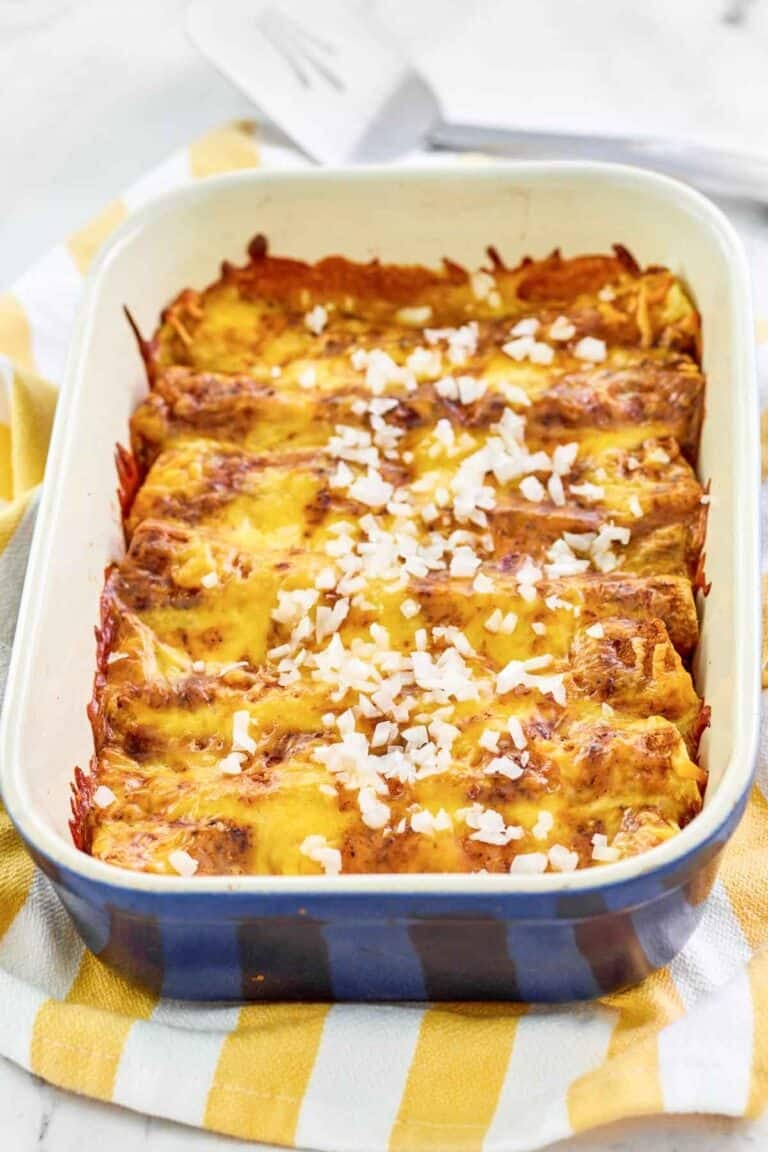 Copycat El Chico cheese enchiladas in a baking dish and a spatula behind it.