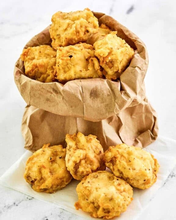 Copycat Fat Ronnie's deep fried mushrooms in a small paper bag and on parchment paper.