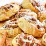 Homemade IKEA cinnamon rolls with icing and two cinnamon sticks.