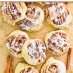 Homemade IKEA cinnamon rolls and cinnamon sticks on parchment paper.