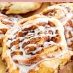 Homemade IKEA cinnamon roll with icing on parchment paper.