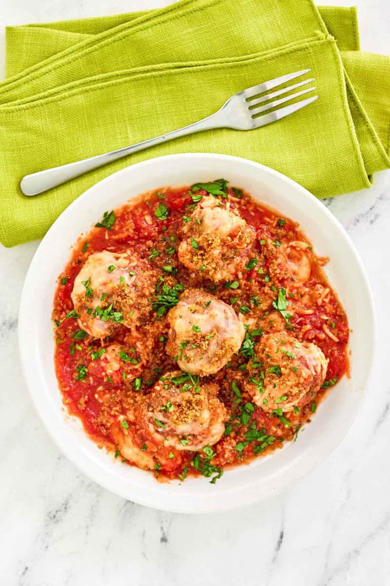 Copycat Olive Garden meatballs parmigiana on a marble surface.