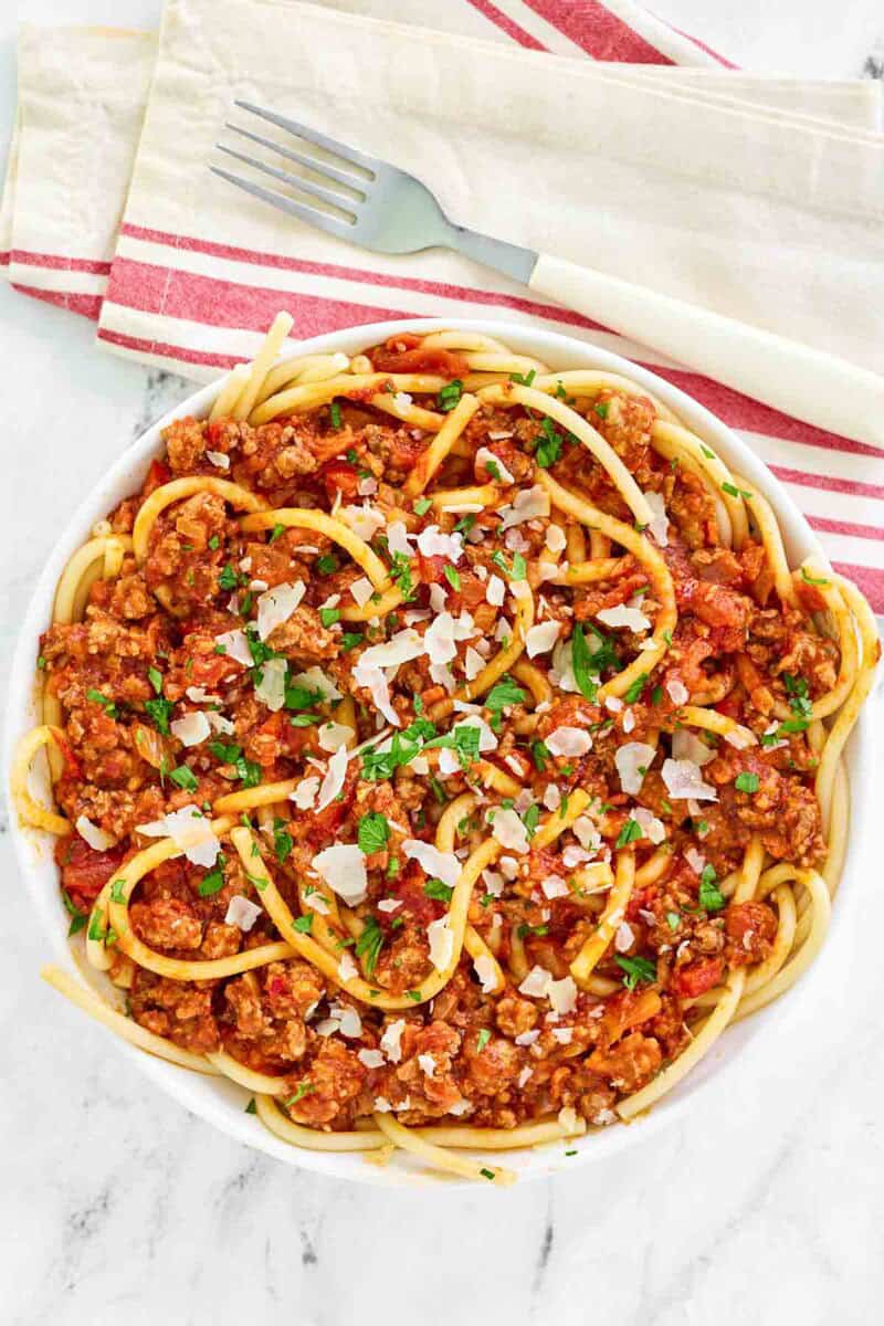 Copycat Olive Garden spicy three meat sauce with bucatini and a fork on a napkin.