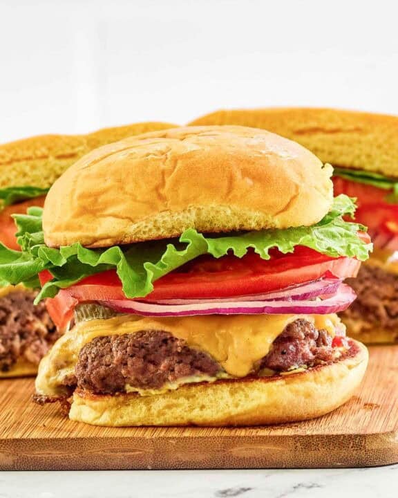 Copycat Smashburger classic smash burger on a small wood serving board.