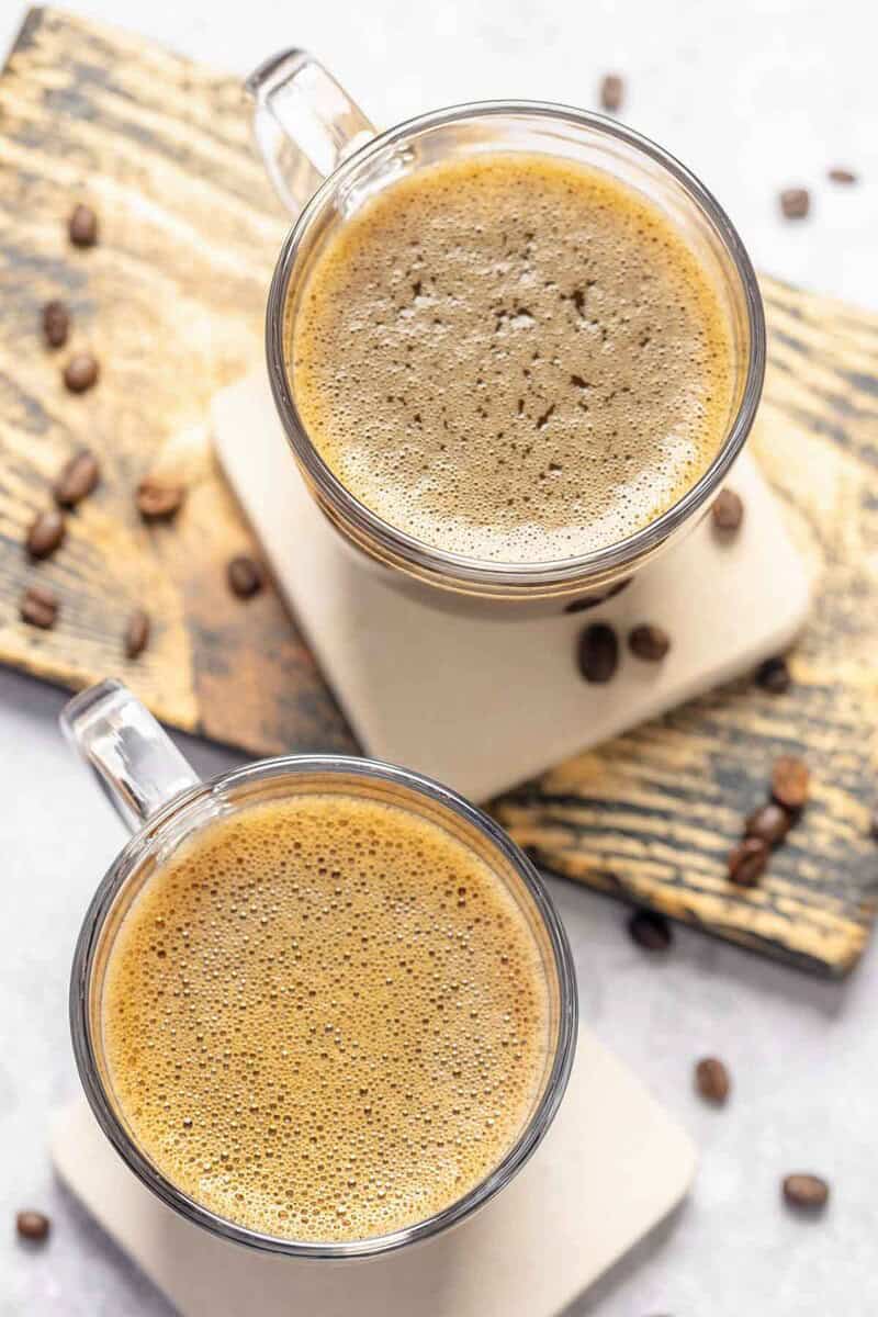 Two copycat Starbucks americano drinks and coffee beans scattered around them.