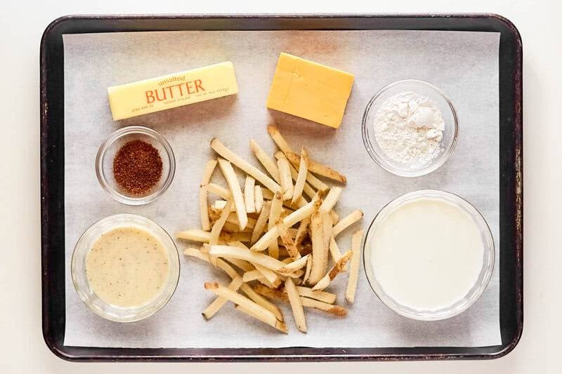Overhead view of Voodoo Fries ingredients: frozen fries, butter, cheese, flour, cream, Cajun seasoning, and ranch dressing.